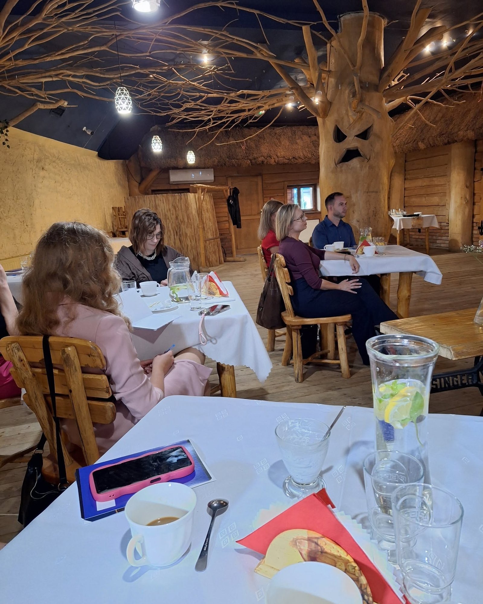 Uczestnicy siedzą przy wspólnych stołach w restauracji